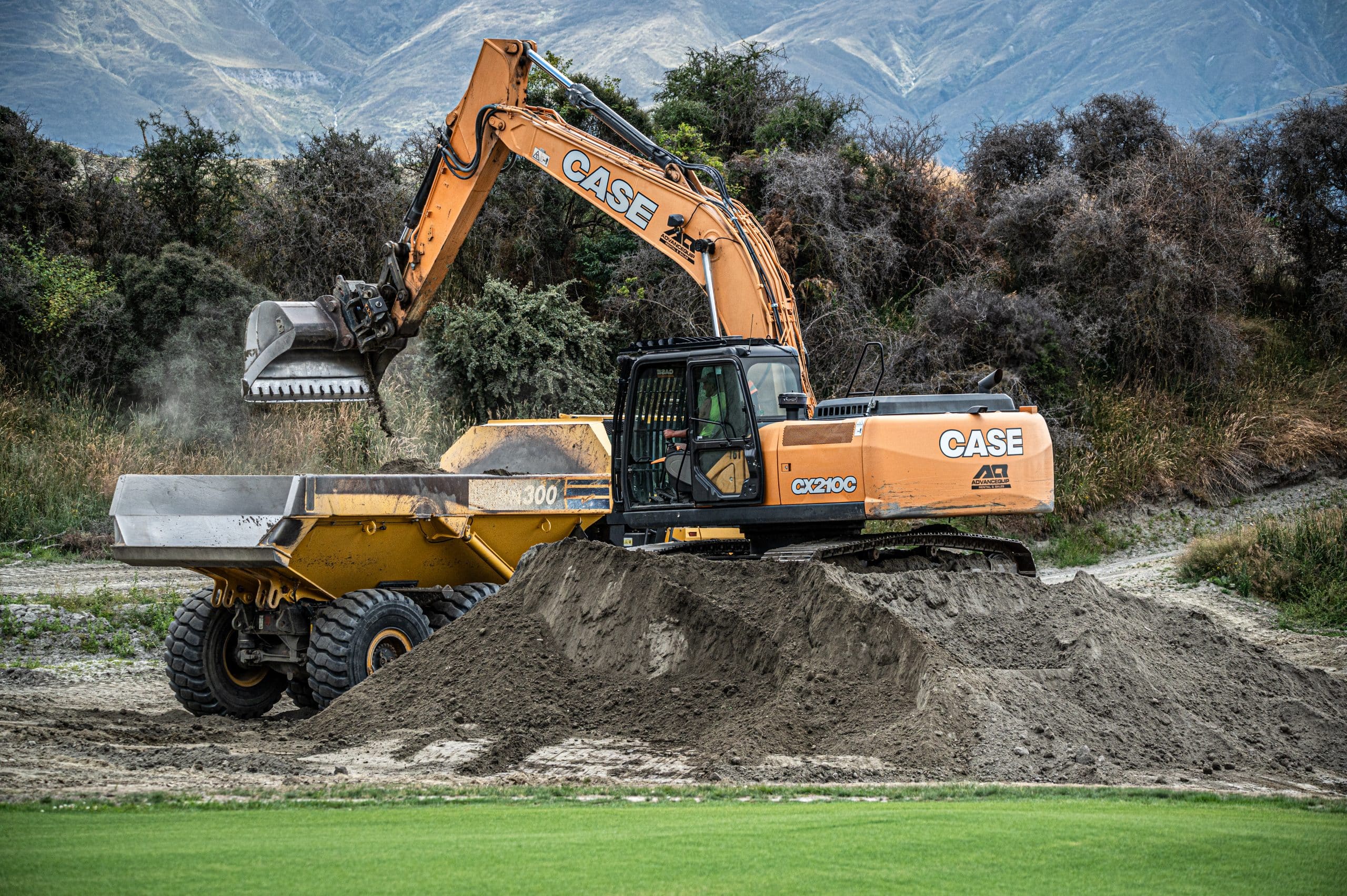 Golf course construction teamwork – CX210C excavator loading HM300 truck